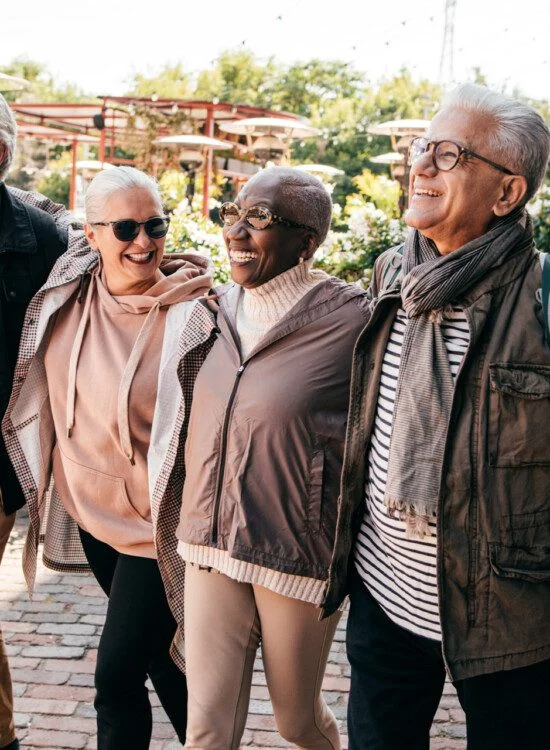 Four people walking happily on a sunny cobblestone street.