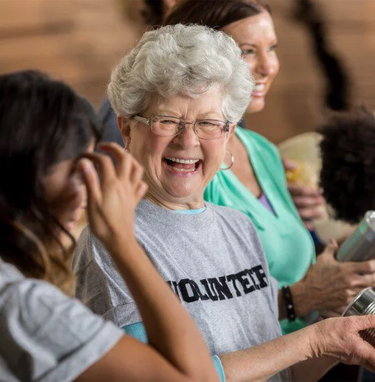 Smiling volunteers holding canned goods at a community event.