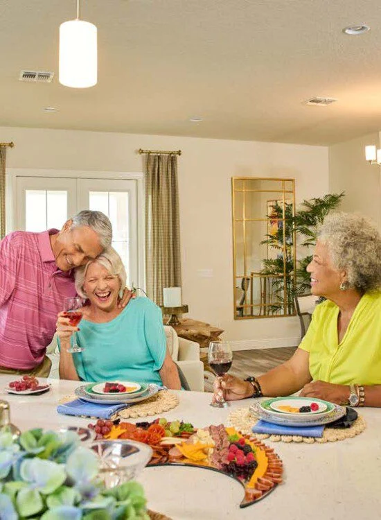 Group of friends enjoying wine and laughter at a dining table.