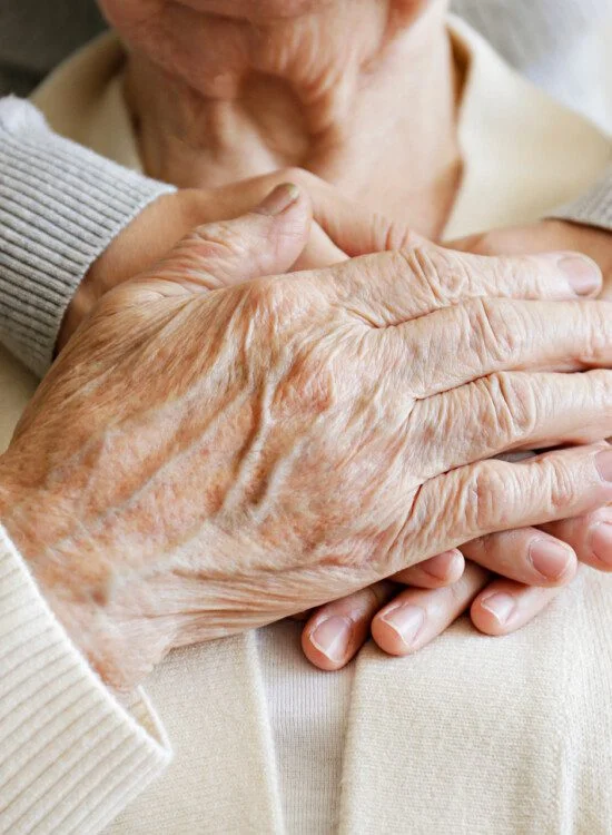 Older adult's hands held by a younger person, showing support.