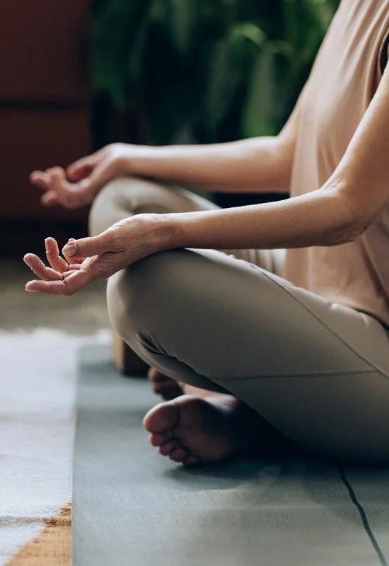 Person meditating cross-legged indoors on a yoga mat.