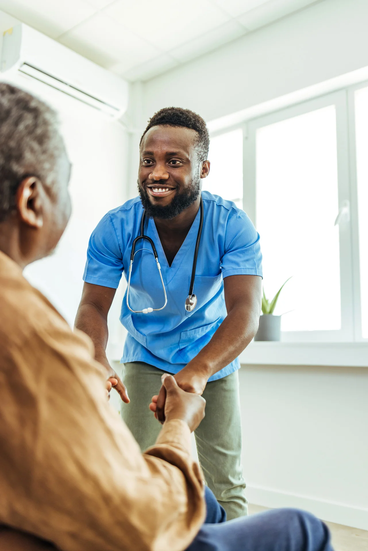 Healthcare worker assisting patient in a bright room.