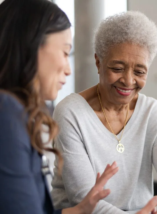 Two women smiling and looking at a tablet together.