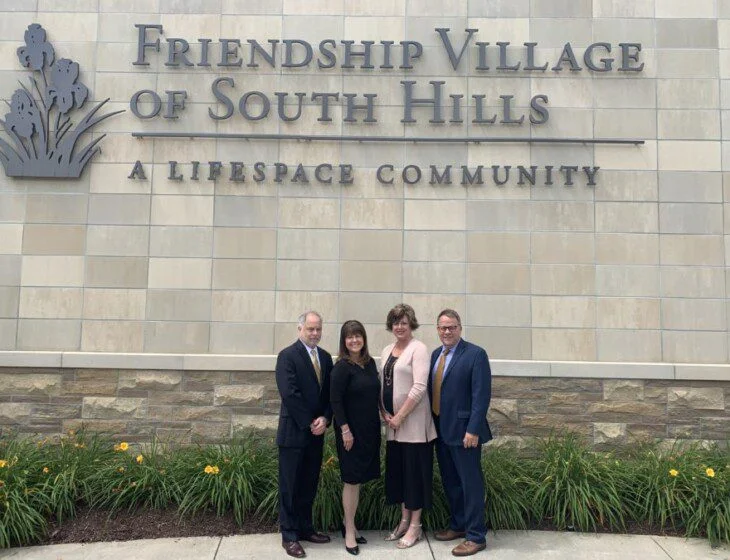 People standing in front of Friendship Village of South Hills sign.