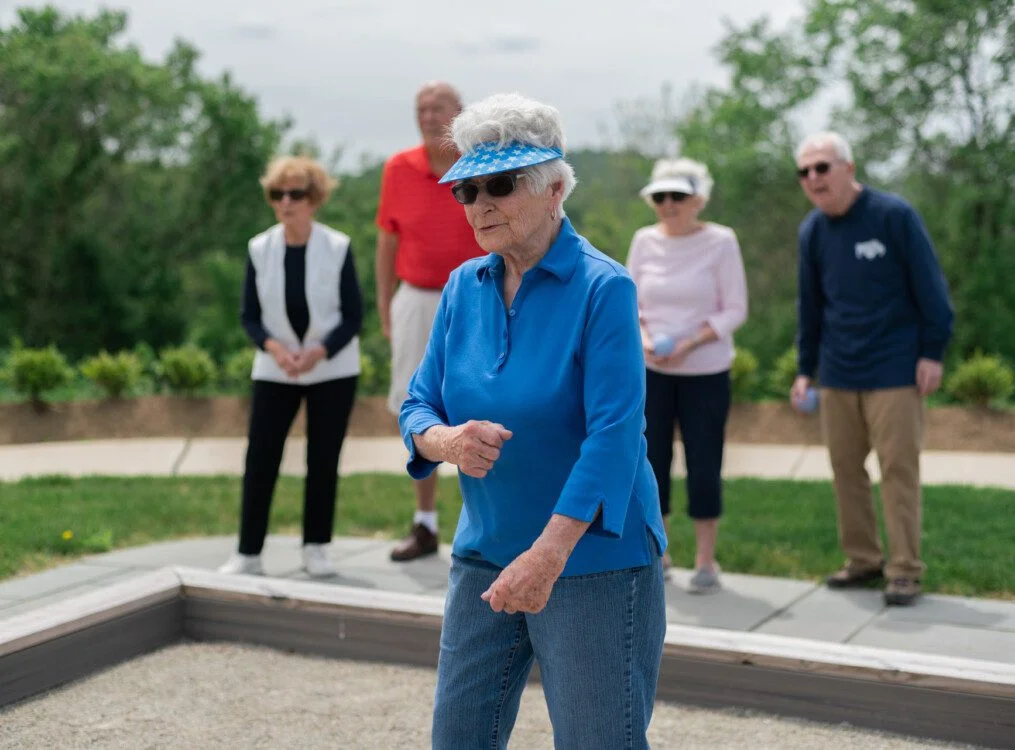 Elderly group playing bocce outdoors on a sunny day.