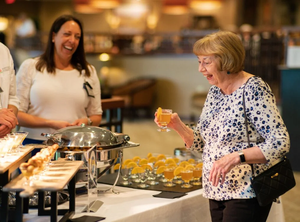 Woman laughing with a drink at a catered event.