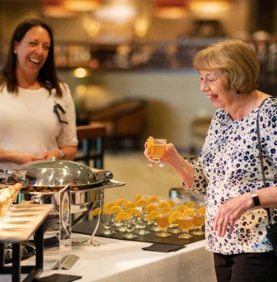 Woman laughing with a drink at a catered event.