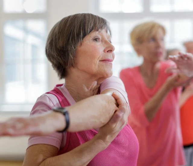 Woman stretching with a group in a bright exercise class.
