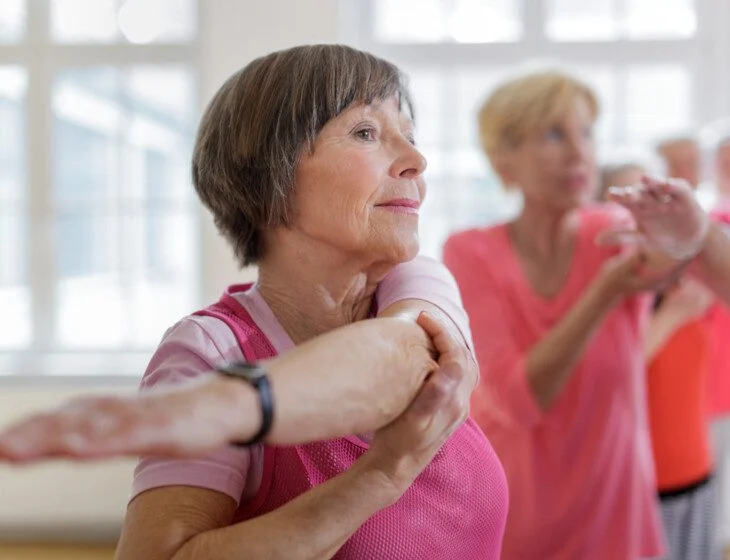 Woman stretching with a group in a bright exercise class.