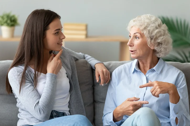 Two women sitting on a couch, engaged in lively conversation.