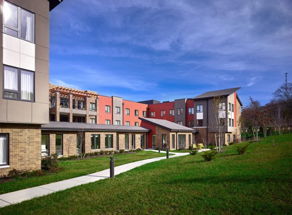 Modern building with colorful facade and landscaping under a clear blue sky.