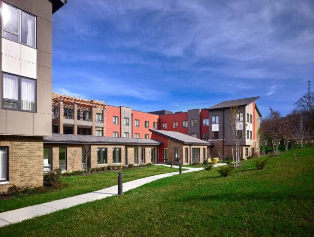 Modern building with colorful facade and landscaping under a clear blue sky.