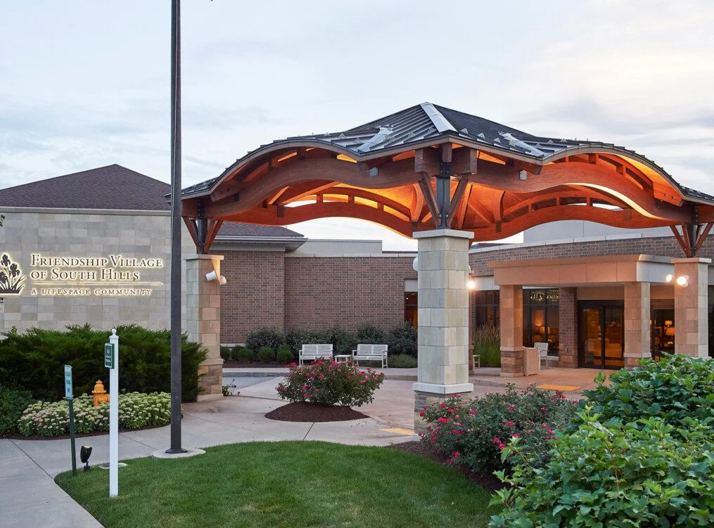 Entrance to Friendship Village of South Hills with a modern canopy and landscaped garden.