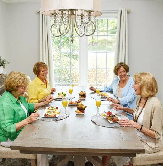 Four women enjoying brunch together at a dining table with bright decor.