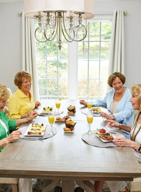 Four women enjoying brunch together at a dining table with bright decor.