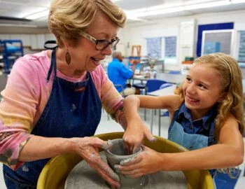 Jad Ryherd Photography, Architectural Photography. lifestyle photography,  Commercial photography, Corporate photography,  St. Louis Missouri , Jad Child and adult smiling while working on pottery at a spinning wheel in a classroom.