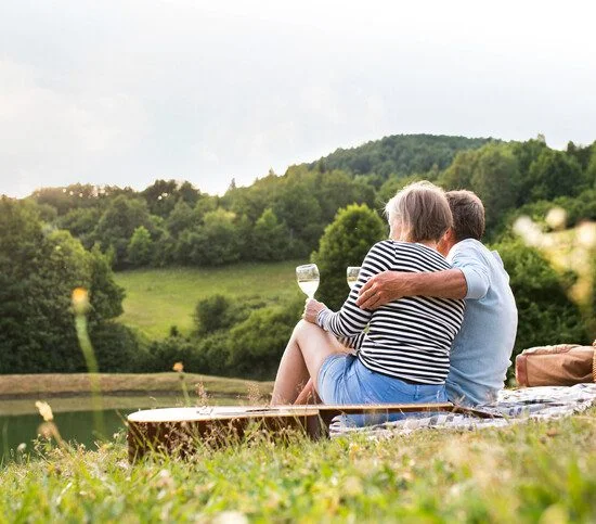 Couple sitting on a blanket, enjoying wine with a scenic view.