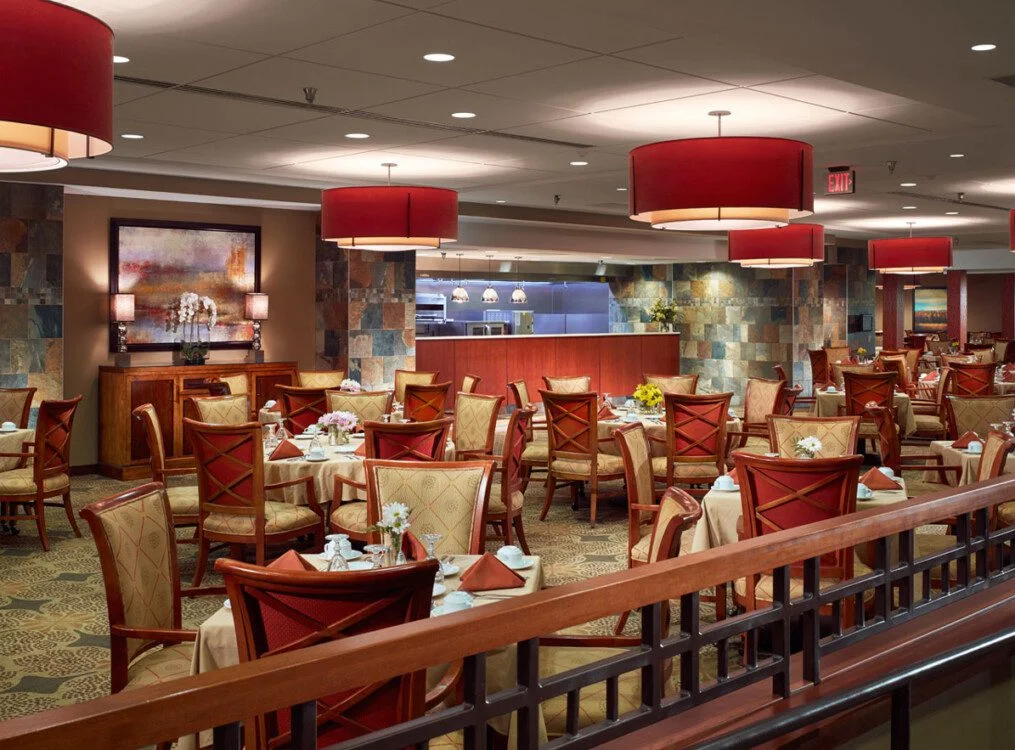 Spacious restaurant with elegant decor, red accents, and neatly arranged dining tables.