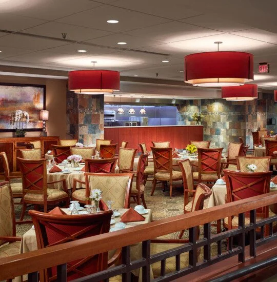 Spacious restaurant with elegant decor, red accents, and neatly arranged dining tables.