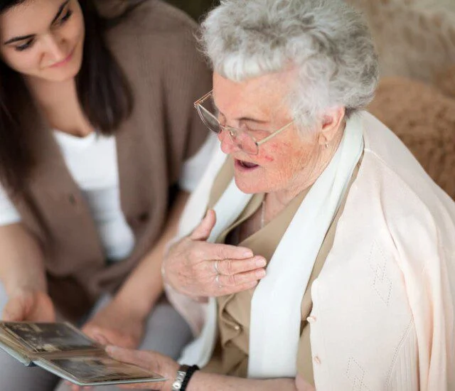 Elderly woman and young woman looking at a photo album together.