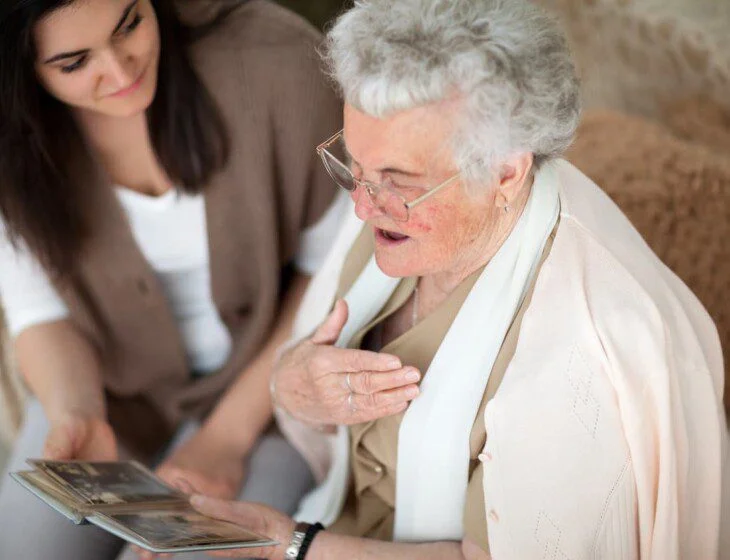 Elderly woman and young woman looking at a photo album together.