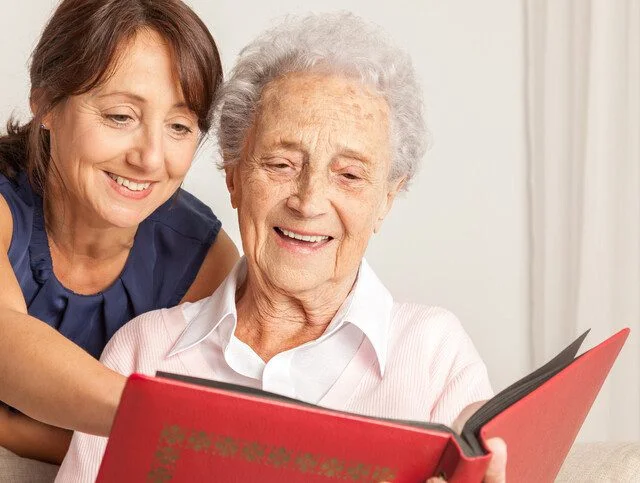 Two women happily looking at a photo album together.