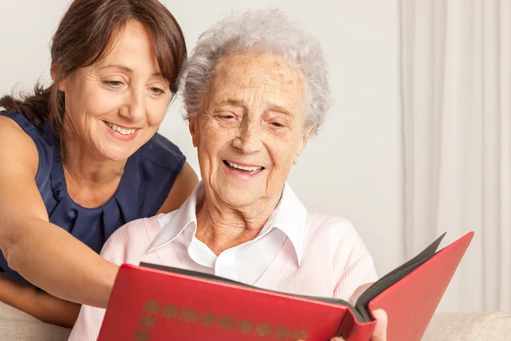 Two women happily looking at a photo album together.
