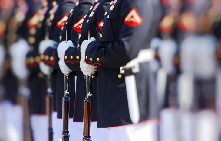 Military officers in uniform standing in formation, holding rifles.