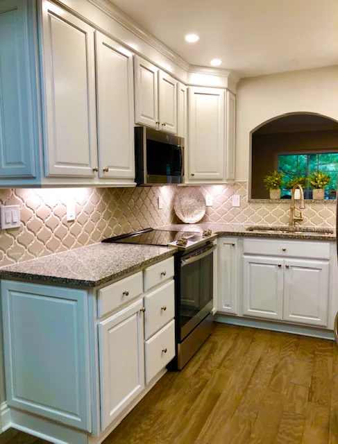 Modern kitchen with white cabinets, granite countertops, and stainless steel appliances.