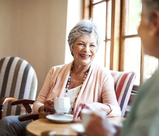 Senior living residents engaging in conversation over coffee.