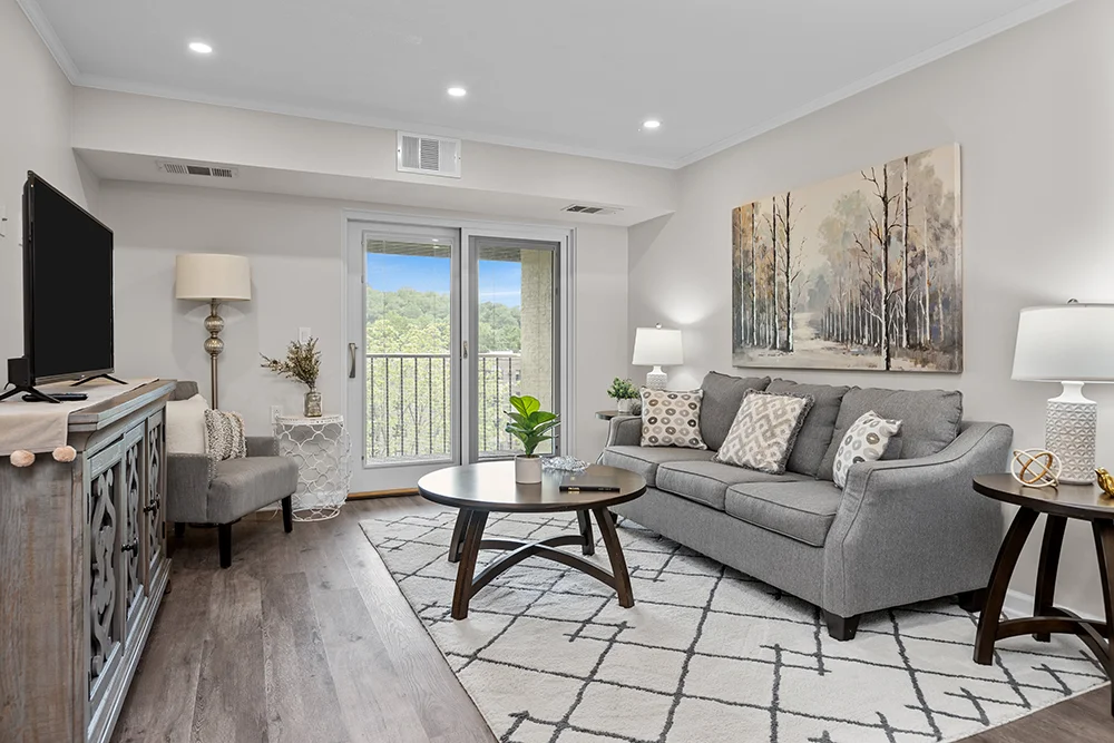 Modern living room with gray sofa, chairs, and lamps, featuring a large window view.