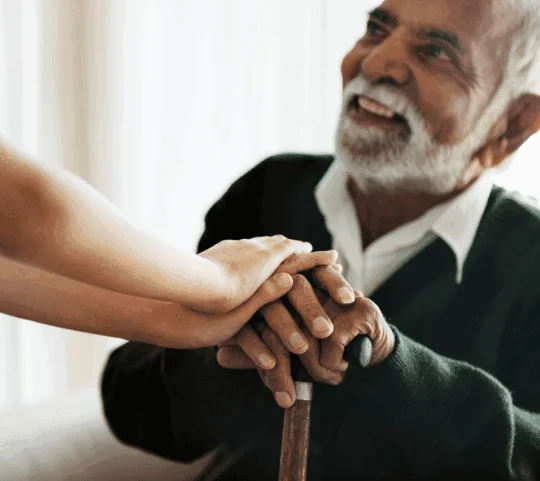 Elderly man smiling, holding hands with a child, symbolizing warmth and connection.