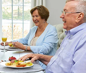 Elderly couple dining and smiling together at a table.