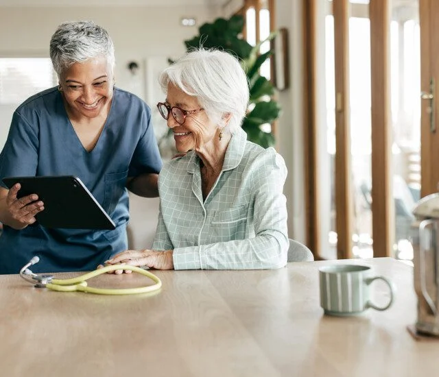 A compassionate nurse helping an elderly woman understand her healthcare options at home.