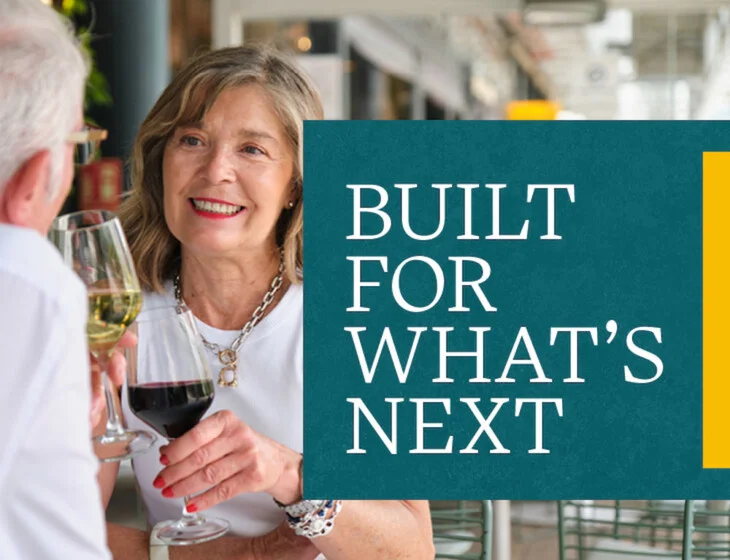 Senior woman facing man with glasses of wine in hand with event text: Built For What's Next