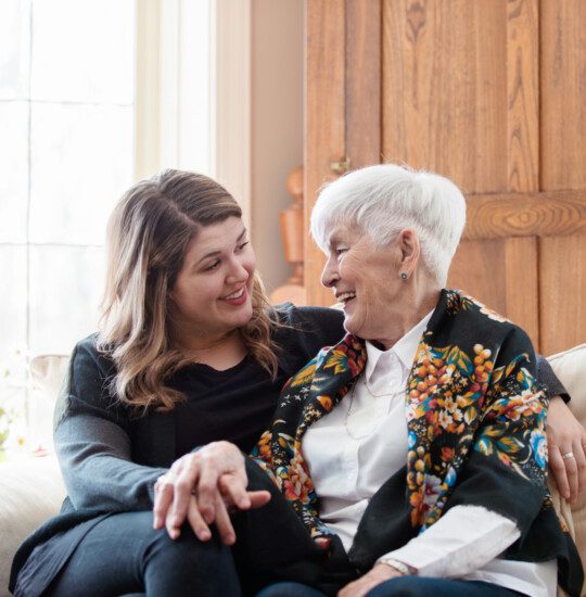 older woman and younger woman on sofa looking at each othwr