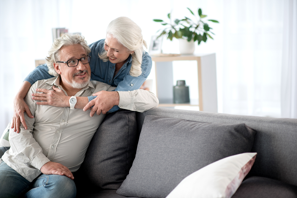 Senior couple hugging while sitting on the couch