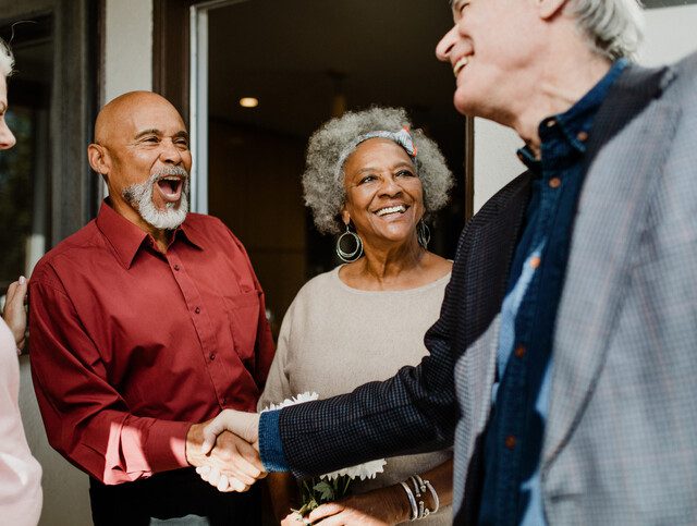 Two older adult couples exchanging greetings.