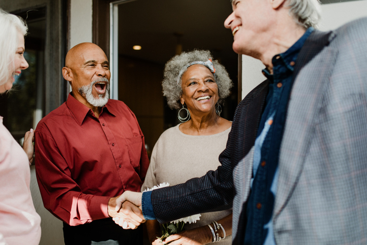 Two older adult couples exchanging greetings.