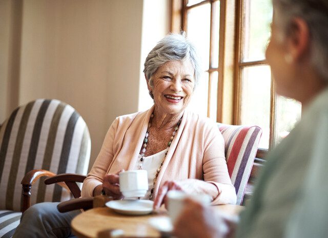 Senior living residents engaging in conversation over coffee.
