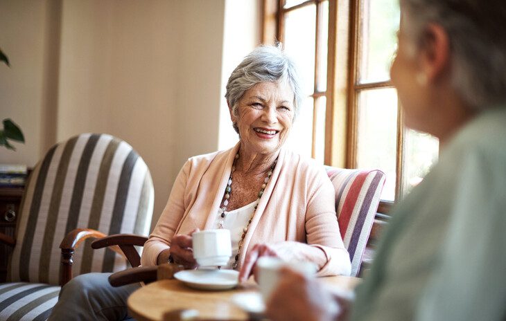 Senior living residents engaging in conversation over coffee.