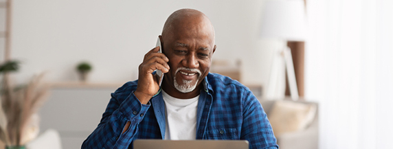 Mature Man Talking On Cellphone And Using Laptop Mature Man Talking On Cellphone Using Laptop In Office